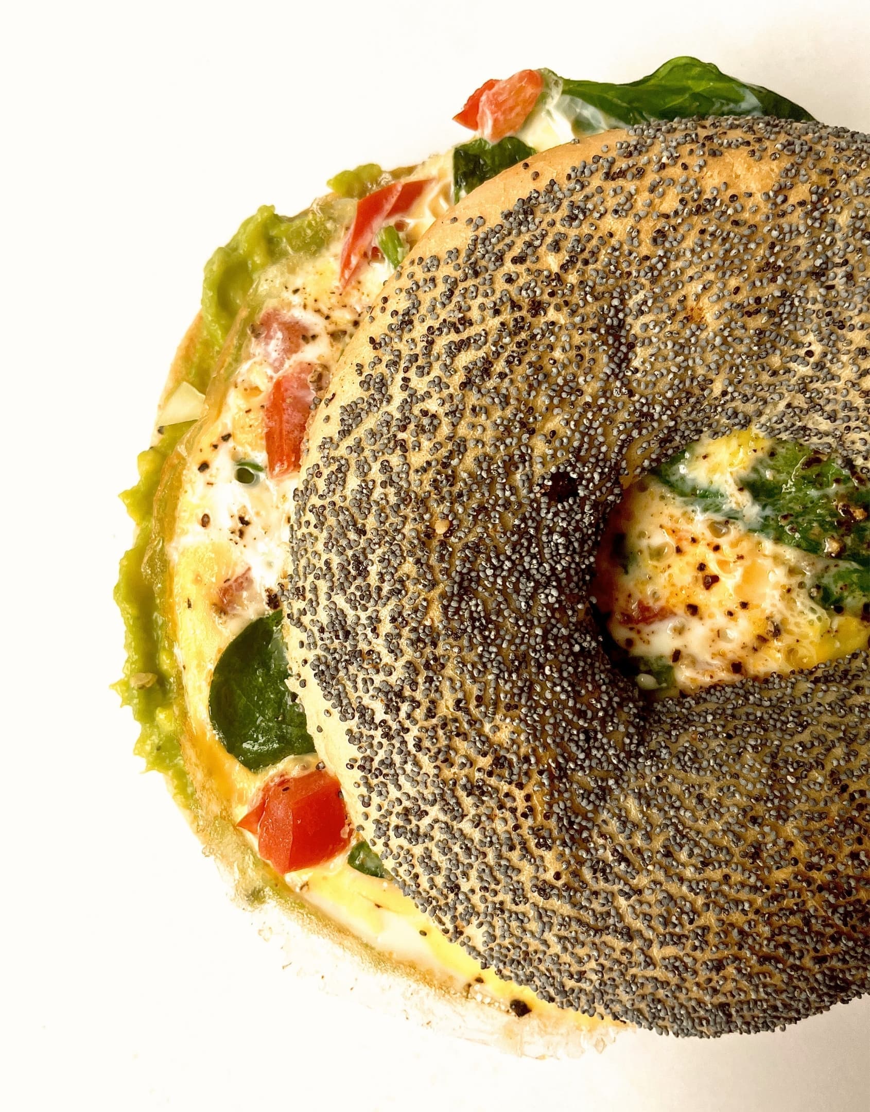 Świeżo przygotowane bajgle z różnymi dodatkami - wędlina, ser, warzywa, serwowane na białym talerzu w Zapini