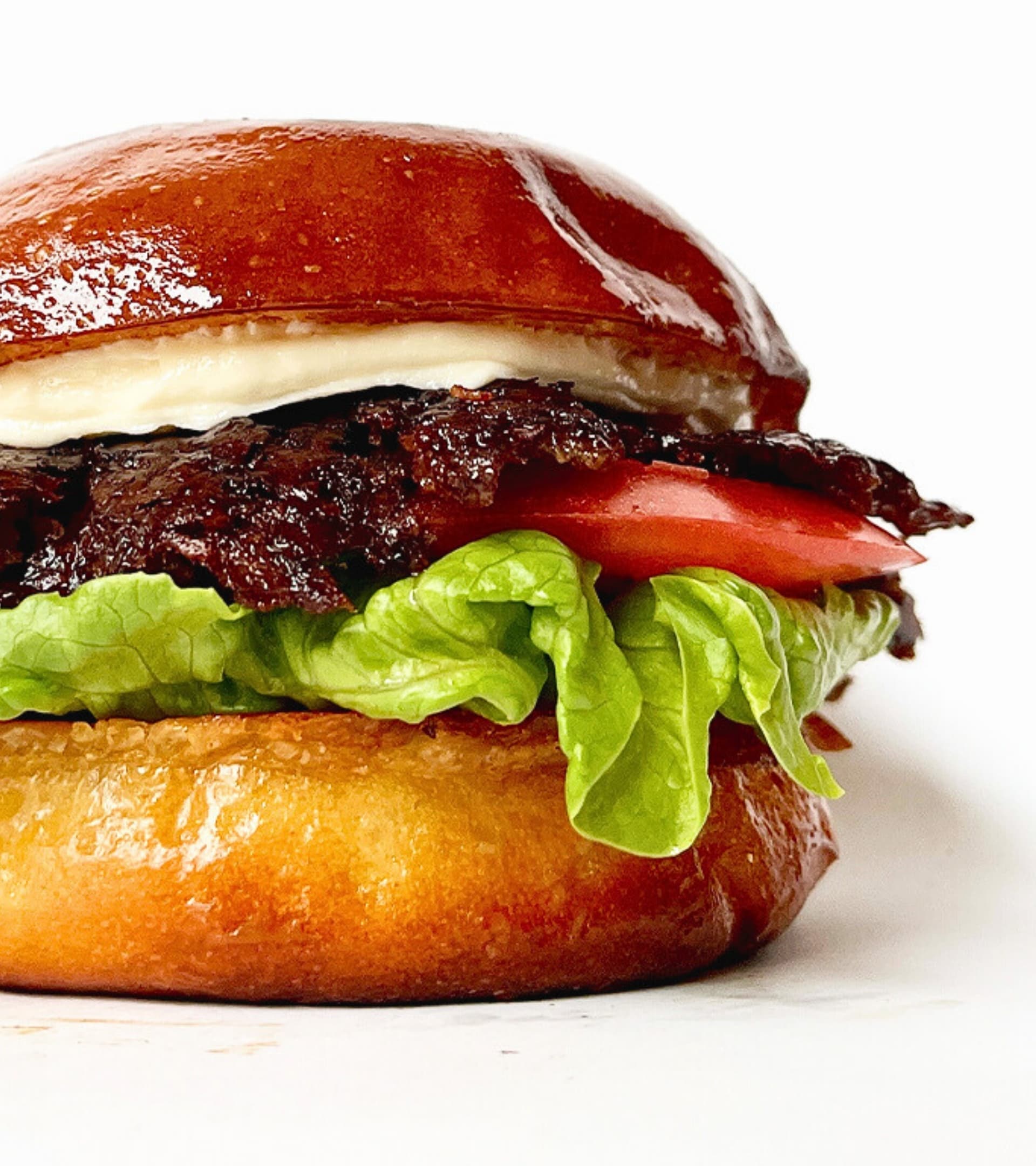 Soczysty smash burger z wołowiną Red Angus, świeżymi warzywami i domowym sosem na drewnianej desce - pokazuje jakość składników w Zapini